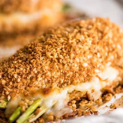 Photo of asparagus stuffed chicken breast filled with mozzarella on a baking sheet.