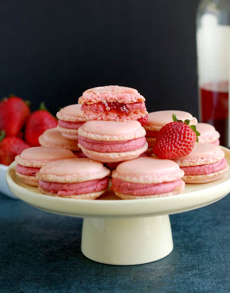 Photo of strawberry rose wine macarons stacked on a white cake stand.