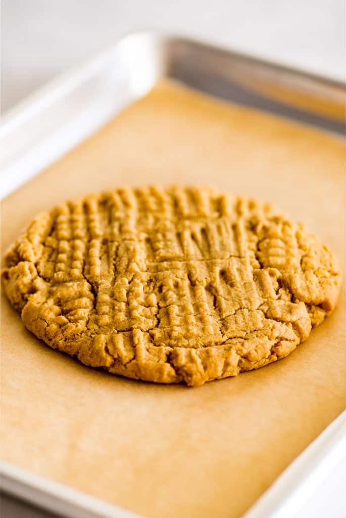 Picture of giant one peanut butter cookie on a quarter sheet baking tray.
