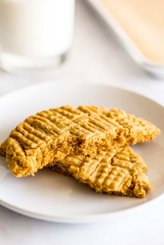 Photo of giant one peanut butter cookie split in half on a white plate.