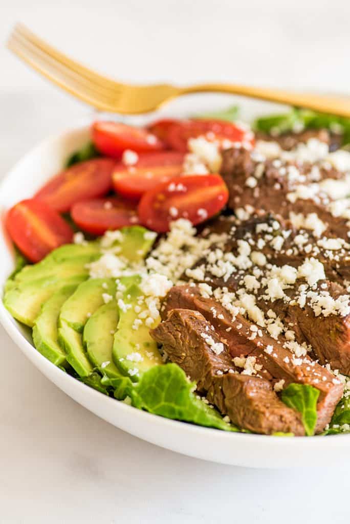 Close up photo of Carne Asada Salad in a white bowl.