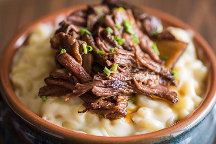 Short Rib Mac and Cheese in a blue bowl with chives sprinkled over the top.