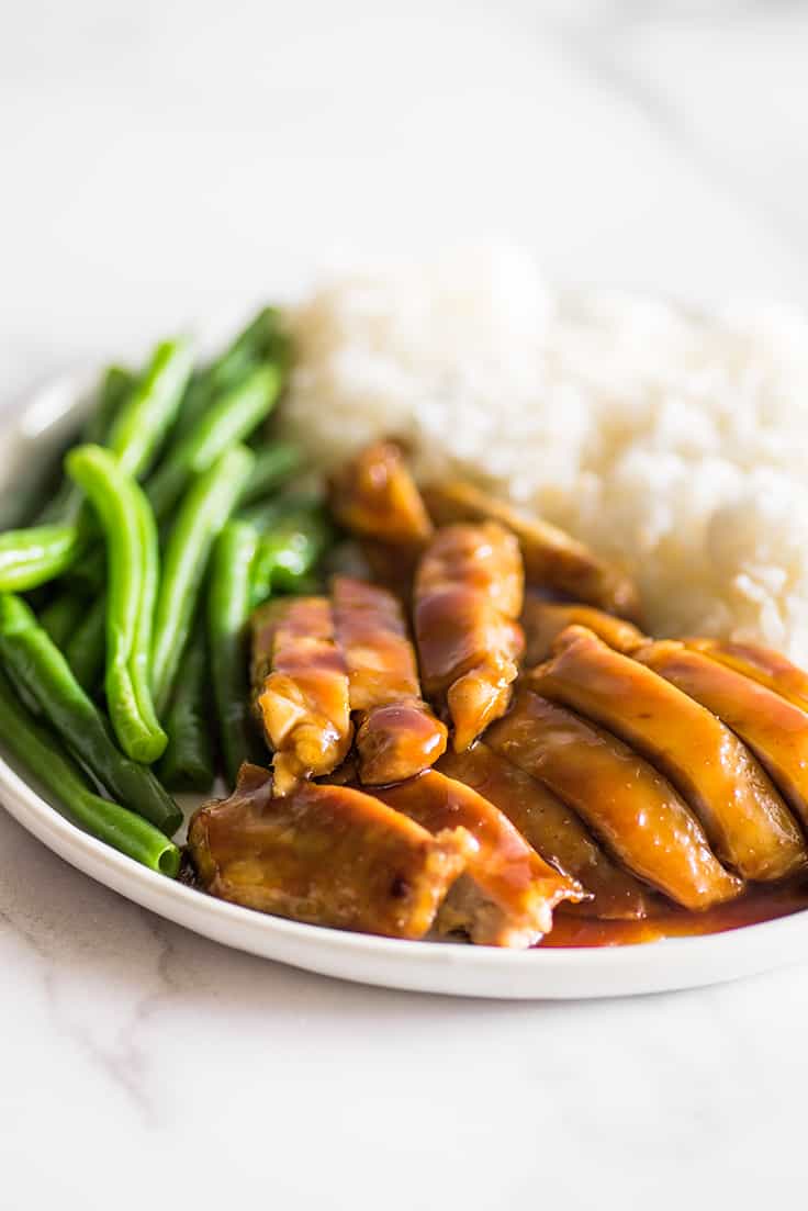 Image of chicken thighs in homemade teriyaki sauce on a plate with green beans and rice.