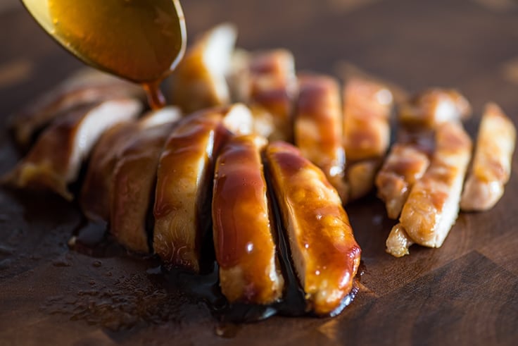 Photo of homemade teriyaki sauce being spooned over chicken thighs.