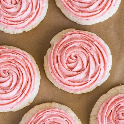 Overhead photo of Lemon Cookies With Strawberry Frosting on parchment paper.
