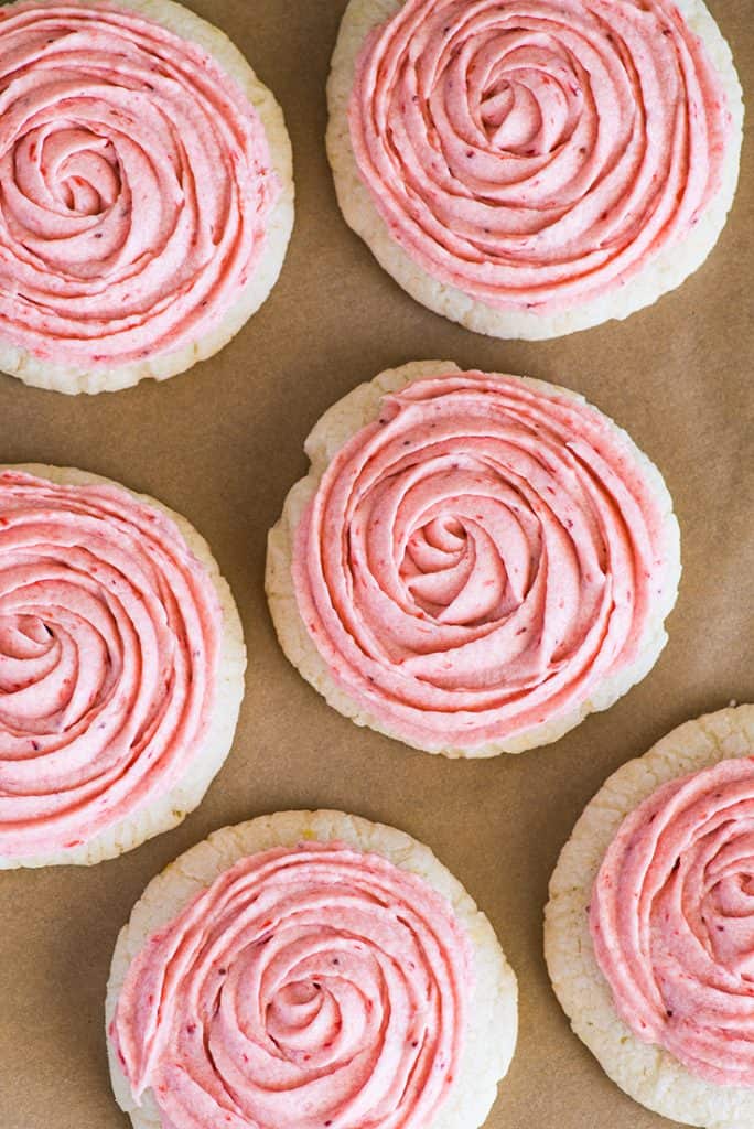 Overhead photo of Lemon Cookies With Strawberry Frosting on parchment paper.