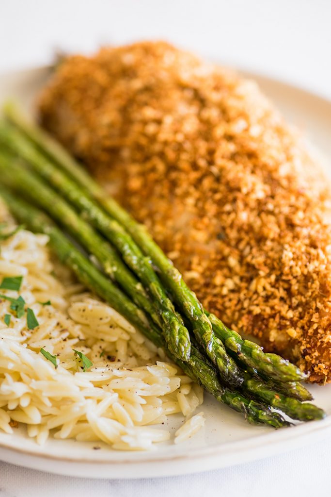 Photo of roasted asparagus on a plate with chicken and orzo.