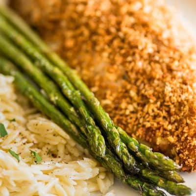Photo of roasted asparagus on a plate with chicken and orzo.