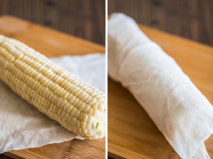 Corn being wrapped in a paper towel to be cooked in the microwave.