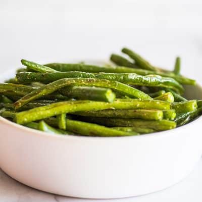 Roasted green beans in a white bowl.