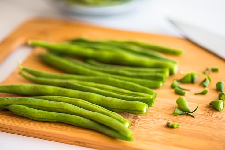 Green beans on a cutting board with ends trimmed.