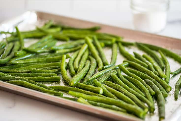 Green beans on a baking sheet before baking.