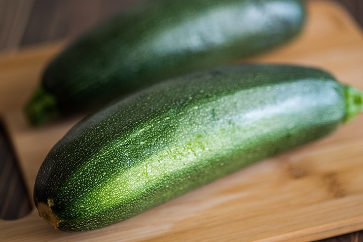 Whole zucchini on a cutting board.