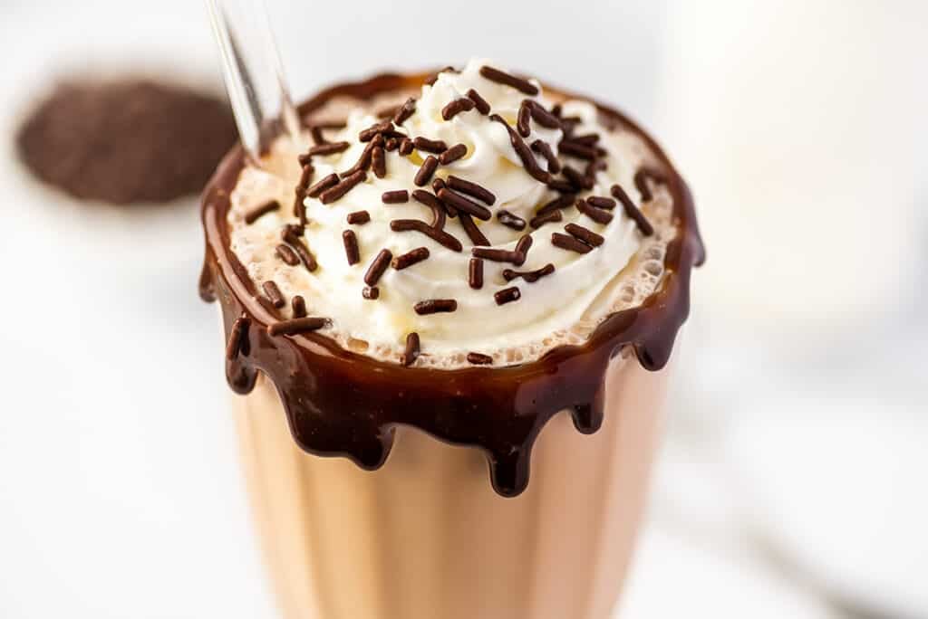 Chocolate milkshake with whipped cream, chocolate sauce, and sprinkles.