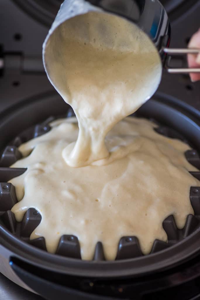 Waffle batter being poured into waffle maker.