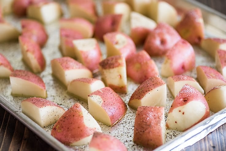 Cut red potatoes for oven-roasting on a baking sheet.