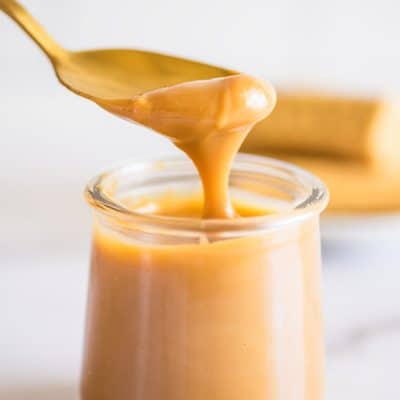Photo of homemade dulce de leche being spooned out of a jar.