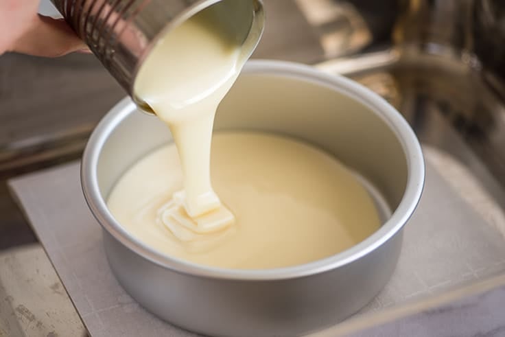 Picture of condensed milk being poured into a cake pan for dulce de leche.