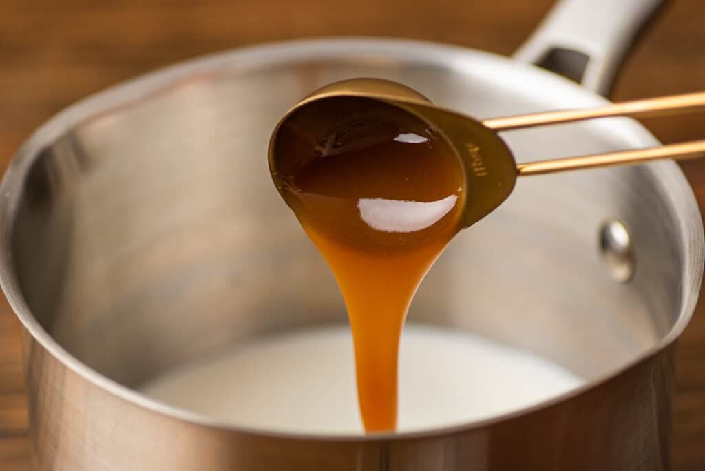 Caramel being poured into milk for a caramel latte.