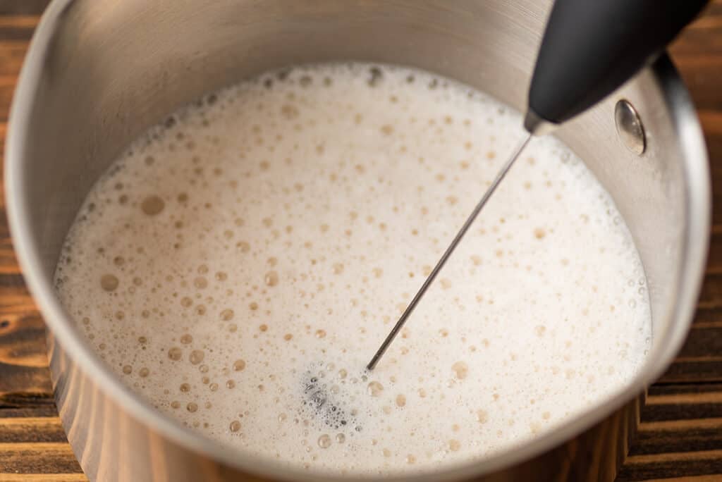 Milk being frothed with a milk frother for a caramel latte.