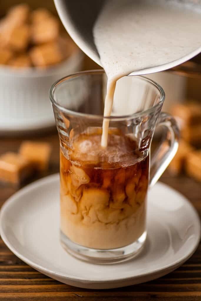 Milk being poured into a caramel latte.