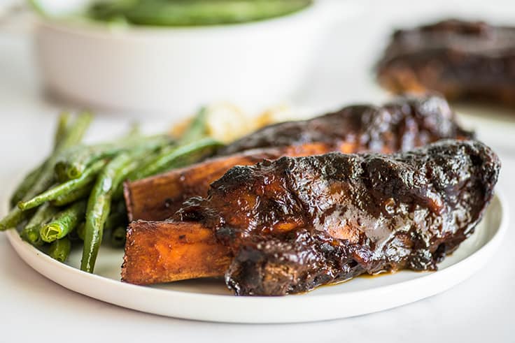 Beef ribs on a plate with green beans.