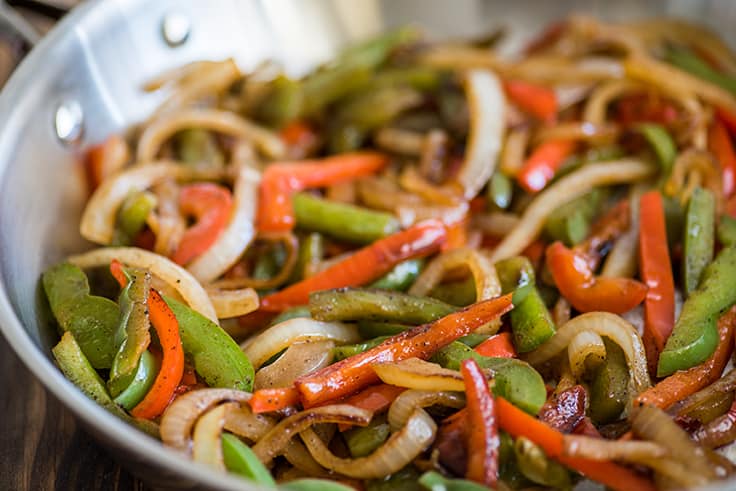 Close up photo of fajita veggies in a pan for steak fajitas.