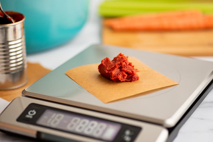 Scoop of tomato paste being weighed for freezing.