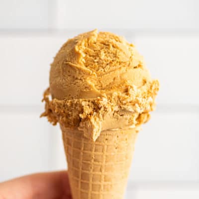 Hand holding Dulce de Leche Ice Cream in a cone.