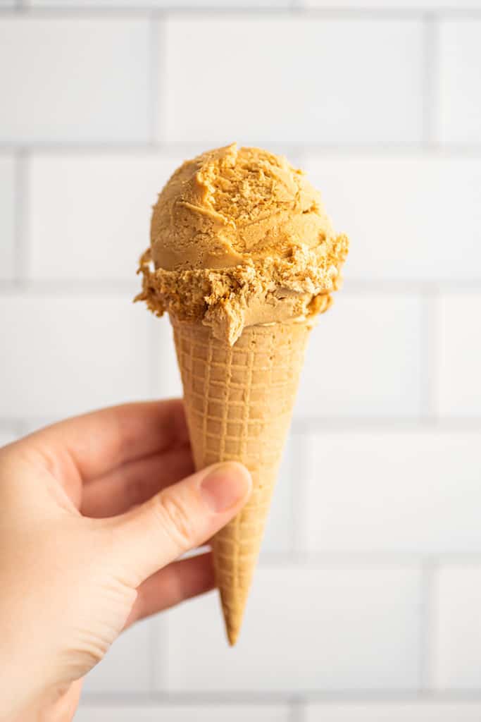 Hand holding Dulce de Leche Ice Cream in a cone.