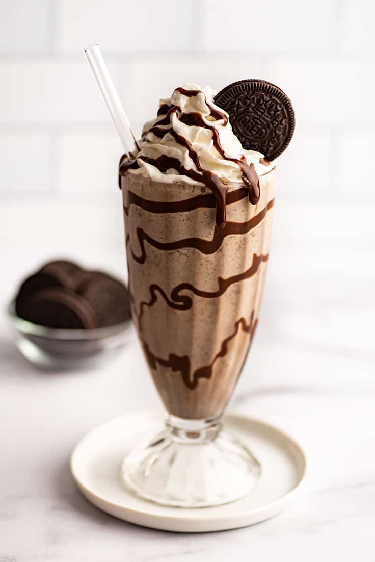 Bailey's oreo shake in a glass cup on a plate.
