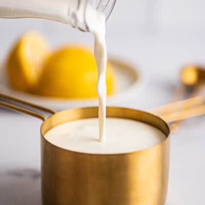 Milk being poured into a measuring up to make buttermilk substitute.