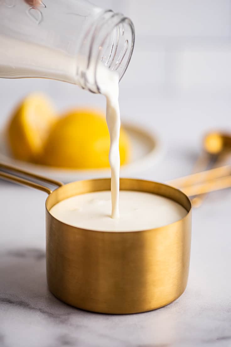 Milk being poured into a measuring up to make buttermilk substitute.
