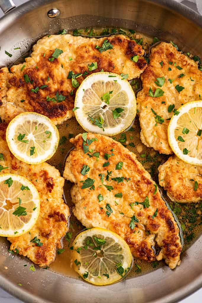 Overhead photo of Chicken Francaise in a pan with lemon slices.