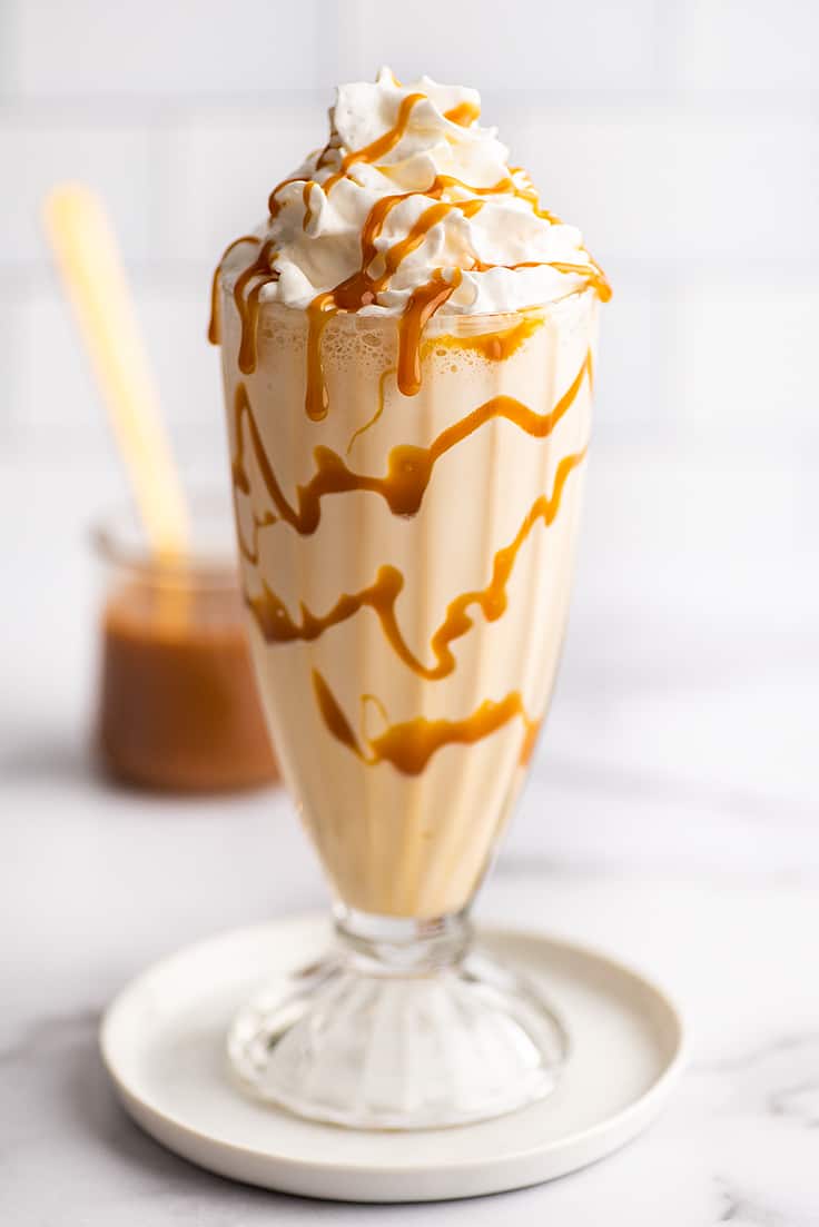 Caramel milkshake in a glass cup with whipped cream.