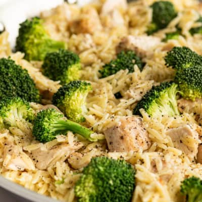 Chicken and broccoli orzo in a skillet.
