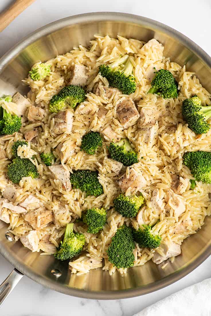 Chicken and orzo with broccoli in a skillet.