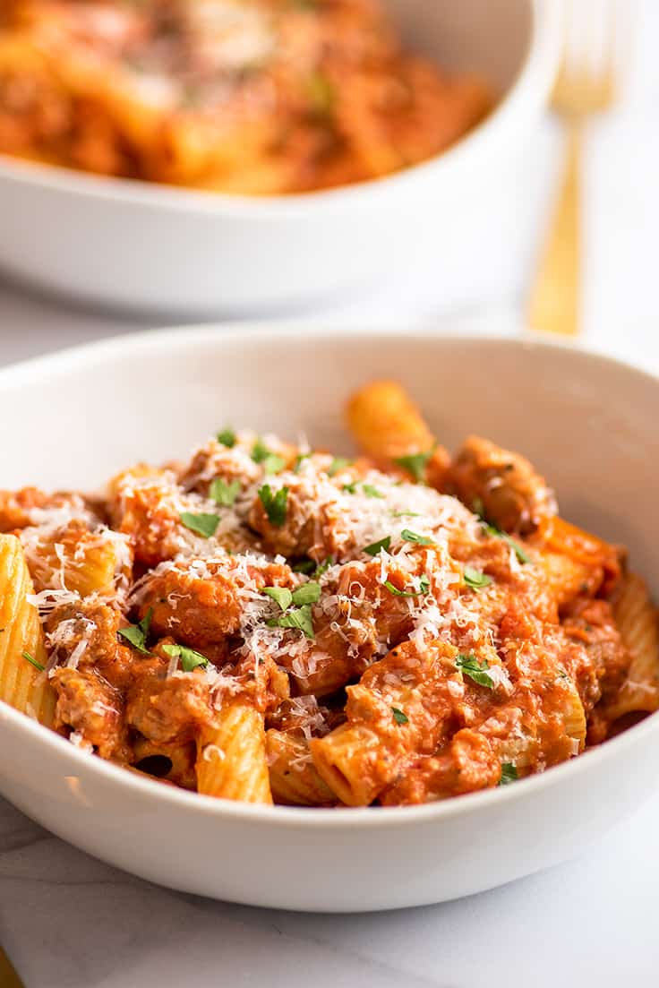 Sausage pasta in a bowl with Parmesan cheese.