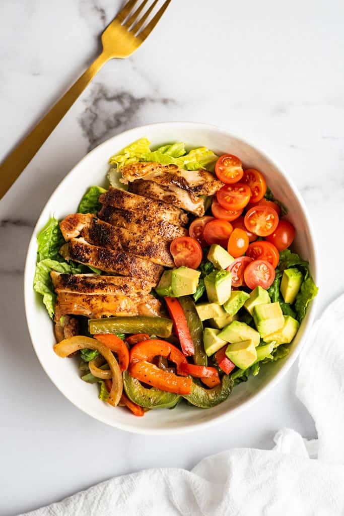 Chicken fajita salad in a white bowl.