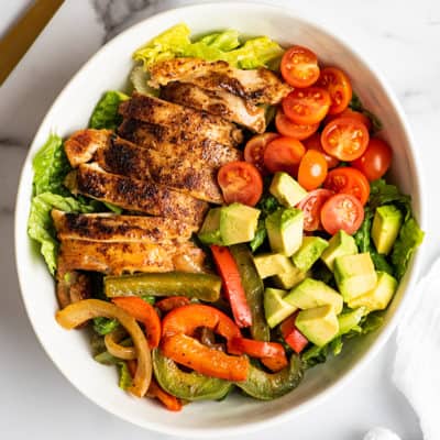 Chicken fajita salad in a white bowl.