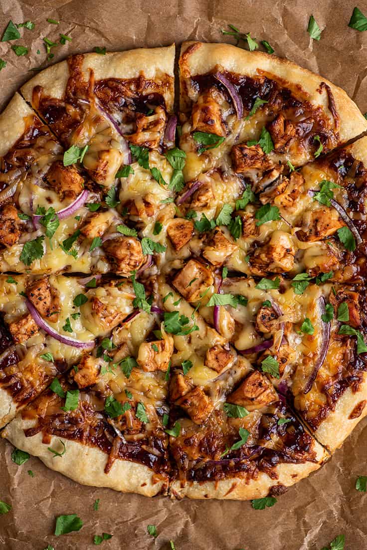 Sliced whole bbq chicken pizza on parchment paper.