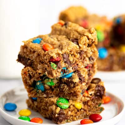 Monster cookie bars stacked on a white plate.