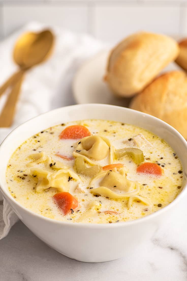 Creamy chicken tortellini soup in a white bowl.