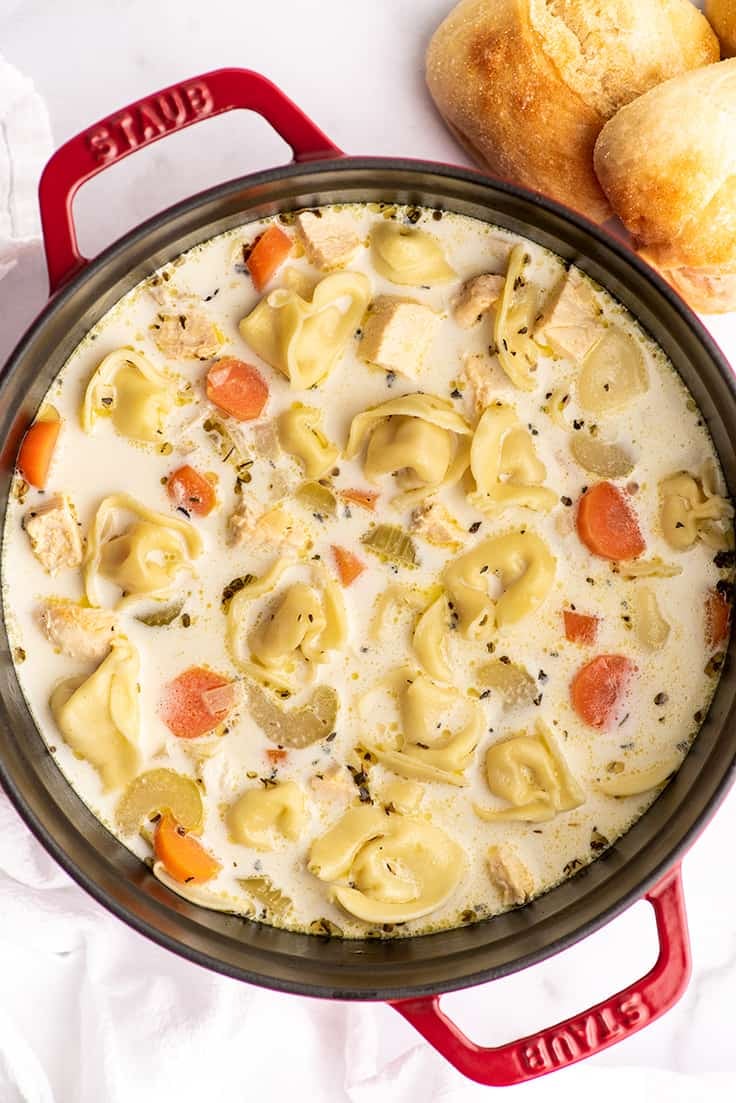 Chicken tortellini soup in a red pot.
