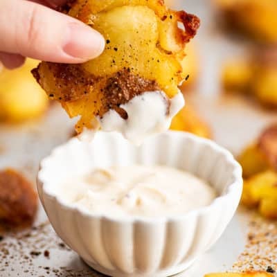 Smashed red potato being dipped in aioli.