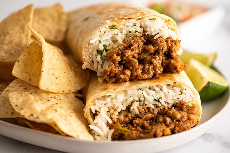 Close up photo of freezer burritos stacked on a plate.
