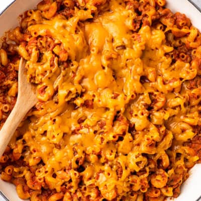 American goulash with cheese in a white Dutch oven.