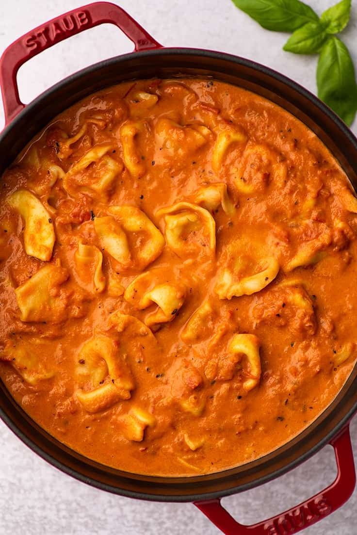 Tomato soup with tortellini in a red Dutch oven.