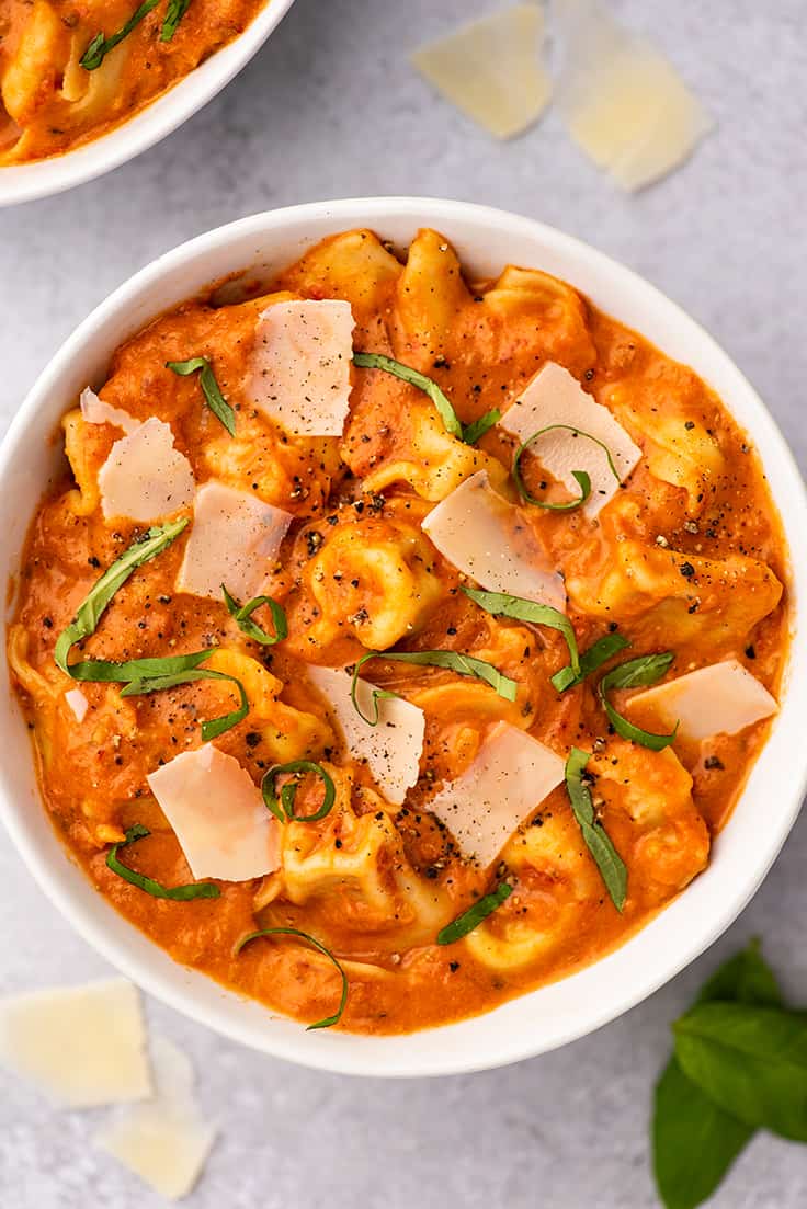Tomato tortellini soup in a white bowl.