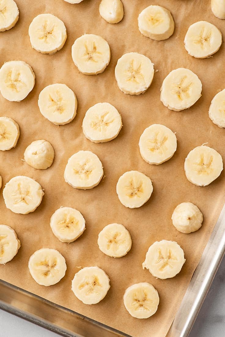 Photo showing how to freeze bananas as slices on a baking sheet.